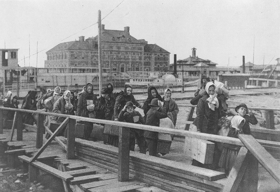 1902 photo of immigrants carrying luggage at Ellis Island