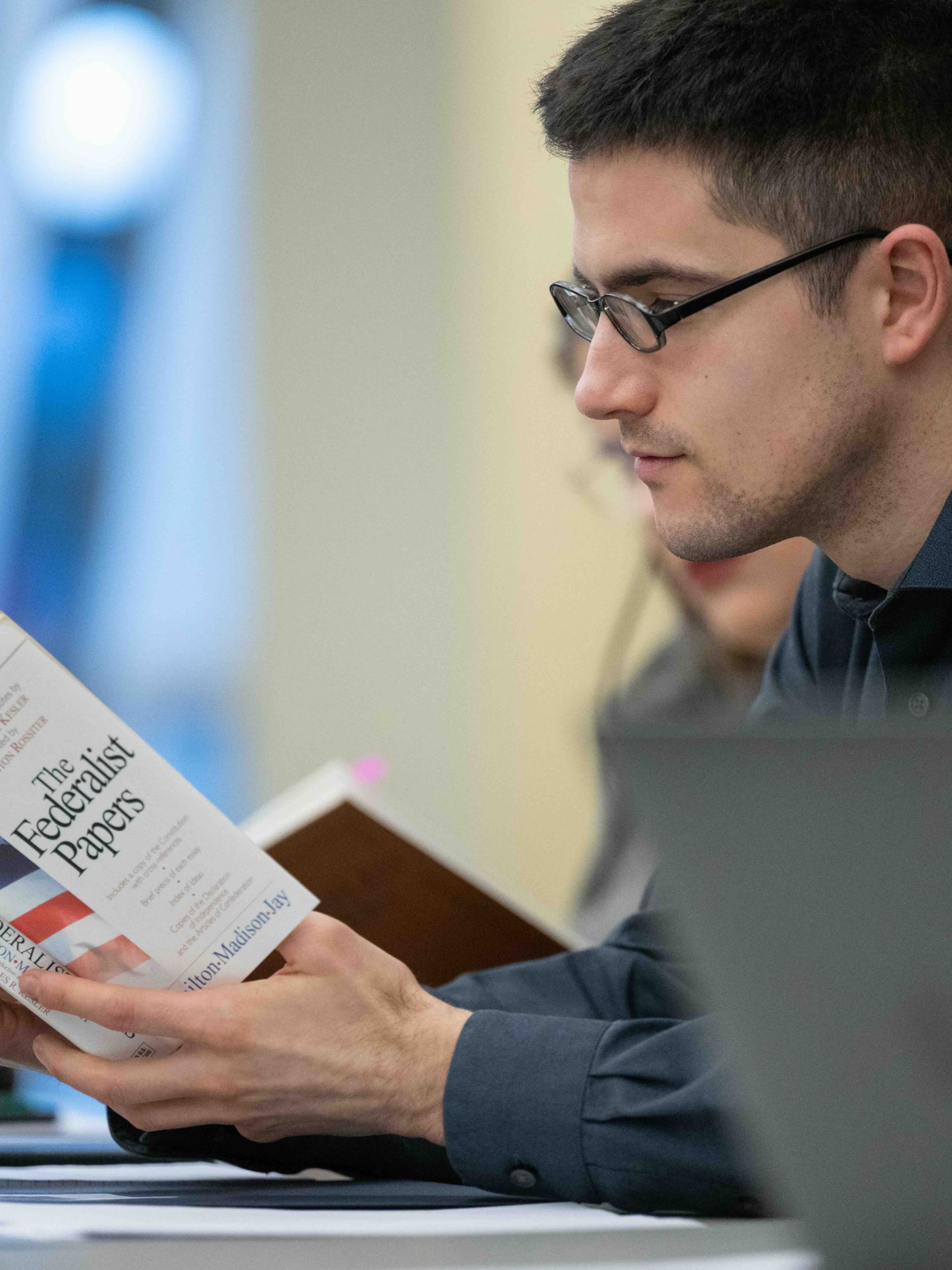 A man reads The Federalist Papers at a JMC-sponsored event.