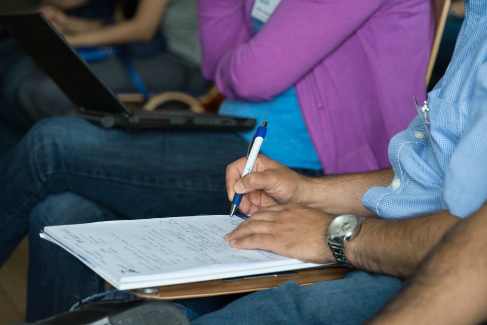 A closeup photos of students' hands as they take notes.