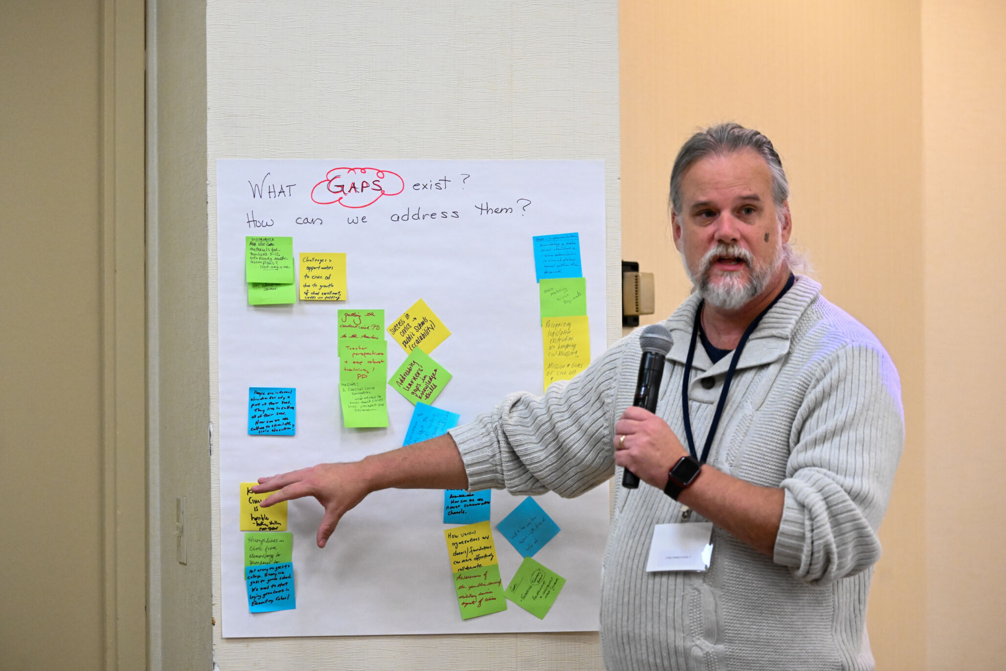 A 2024 Summit participant speaks while pointing to different post-it notes on a whiteboard